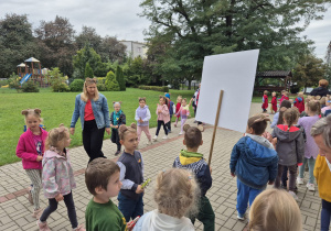 grupa dzieci i ich panie podczas zabawy muzycznej w ogrodzie przedszkolnym