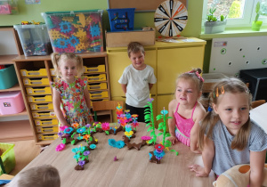 Dzieci pozują do zdjęcia i prezentują swoją budowle wykonaną z klocków.