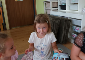 Dziewczynka prezentuje zdjęcia i pamiątki z wakacji.