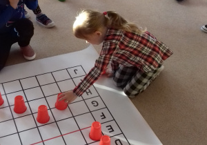 dziewczynka układa czerwony kubek na macie do kodowania