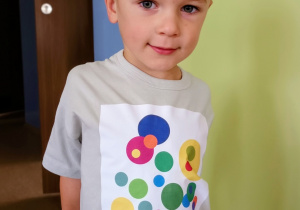 Chłopiec pozuje do zdjęcia. Ma na sobie koszulkę w kropki.