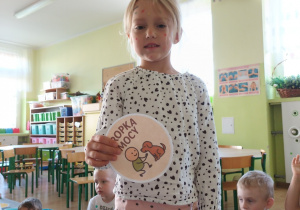 Dziewczynka pozuje do zdjęcia i prezentuje koło z napisem "Kropka mocy".