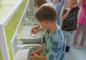 Dziewczynka i chłopiec myją jabłka w łazience.