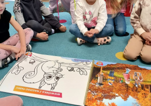 grupa dzieci zgromadzona przed planszami edukacyjnymi związanymi z jesienia
