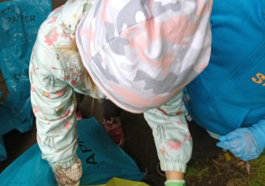 dziewczynka wrzuca śmiecia do worka na odpady