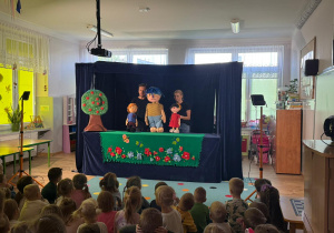 publicznośćuchwycona "od tyłu", w głebi scena i aktorzy animujący lalkami teatralnymi