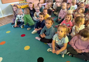 grupa dzieci siedzi na dywanie i ogląda przedstawienie