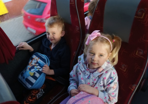 Chłopiec i dziewczynka siedzą w autobusie i pozują do zdjęcia.