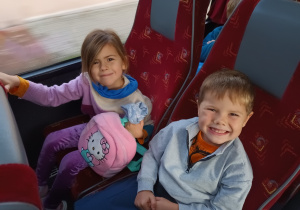 Chłopiec i dziewczynka siedzą w autobusie i pozują do zdjęcia.