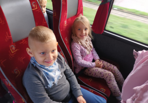 Chłopiec i dziewczynka siedzą w autobusie i pozują do zdjęcia.
