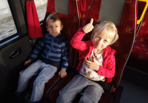 Chłopiec i dziewczynka siedzą w autobusie i pozują do zdjęcia.