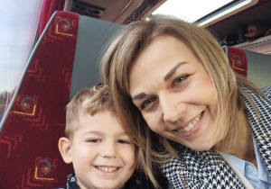 Nauczycielka i chłopiec siedzą w autobusie i pozują do zdjęcia.