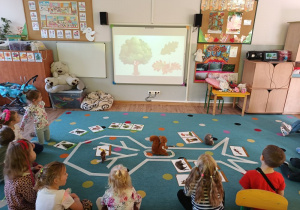 dzieci oglądają film edukacyjny o drzewie