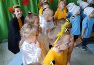 kilkoro dzieci, w szatkach Duszków , stoją podczas występu, obok dzieci z innych grup, w tle dekoracja
