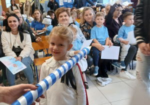 dziewczynka przebrana za biedronkę ma na ramieniu położoną wielką kredkę do pasowania , w tle inne osoby