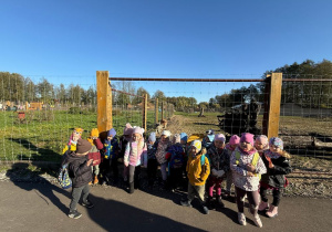 grupa dzieci pozuje do wspólnego zdjęcia , za nimi ogrodzenie minizoo w Dobroniance