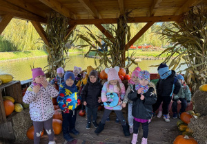 grupa dzieci w altanie pozuje do zdjęcia, na drugim planie staw