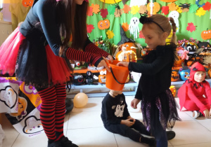 Dziewczynka częstuje się cukierkiem, który podaj jej nauczycielka.