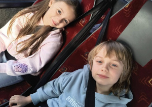 Chłopiec z dziewczynką siedzą w autokarze i pozują do zdjęcia.