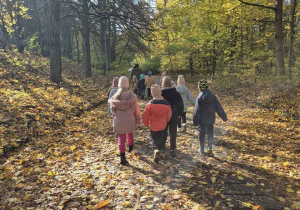 Dzieci spacerują po jesiennym lesie.
