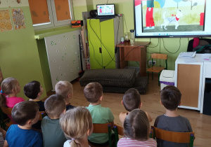 Dzieci siedzą przed ekranem i oglądają film związany z tematem.