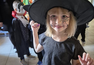 Dziewczynka przebrana za czarownicę pozuje do zdjęcia.