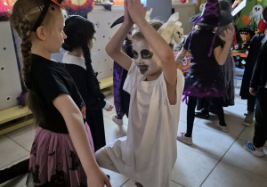 Dzieci tańczą na balu. Na pierwszym planie znajduje się dziewczynka przebrana za ducha.