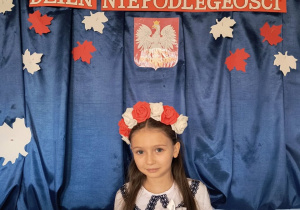Dziewczynka pozuje do zdjęcia na tle dekoracji przygotowanej z okazji Narodowego Święta Niepodległości.