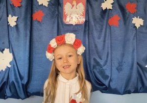 Dziewczynka pozuje do zdjęcia na tle dekoracji przygotowanej z okazji Narodowego Święta Niepodległości.