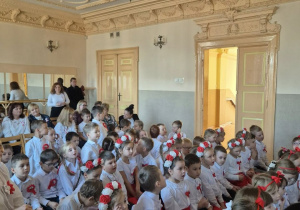 Dzieci w odświętnych strojach siedzą na widowni Młodzieżowego Domu Kultury.