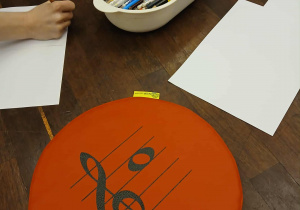 na podłodze leżą mazaki, kartki i podkładka z kluczem wiolinowym