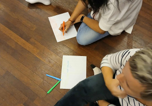 nauczycielki siedzą na podłodze - piszą na kartkach