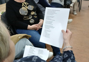 uczestniczki warsztatów podczas spotkania, jedna z pań na pierwszym plani etrzyma w rękach tekst wiersza