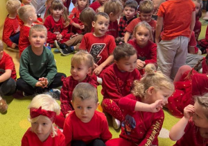 przedszkolaki zgromadzone w klasie, siedzą na dywanie oglądają wystep baletowy