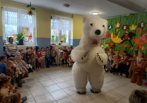 dzieci zgromadzone w szatni, tańczą razem z duzym białym misiem