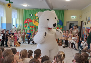 dzieci zgromadzone w szatni, tańczą razem z duzym białym misiem