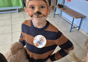 chłopiec z pomalowaną buzia - jako miś, na głowie ma opaskę z uszami