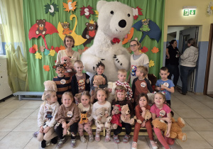 dzieci z grupy Pszczółki oraz nauczycielki pozują do wspólnego zdjęcia z duzym białym misiem