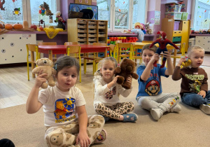 grupa dzieci siedzi na dywanie , w rękach mają pluszaki, uczestniczą w zajęciach