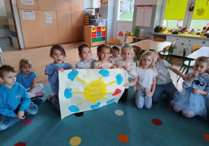 dzieci siedzą na dywanie prezentują wykonany przez siebie plakat z napisem "mam swoje prawa"