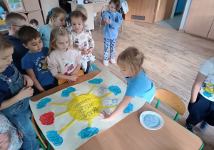 grupa dzieci przy stoliku , wykonują wspólnie plakat o prawach dziecka