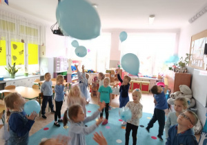 grupa dzieci ubranych na niebiesko bawi się niebieskimi balonami