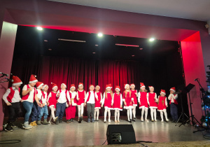 dzieci w mikołajowych strojach tańczy na scenie w MOK