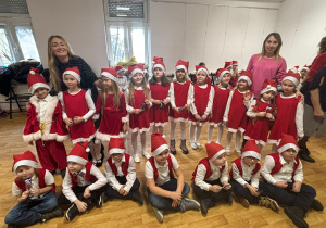 dzieci w mikołajowych strojach oraz ich panie pozujądo zdjęcia za kulisami sceny na scenie w MOK