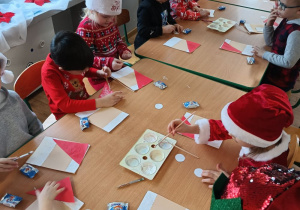 dzieci przy stolikach wykonują pracę plastyczną