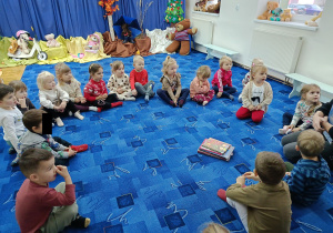 grupa dzieci w bibliotece, siedzą w kole i słuchają pani bibliotekarki