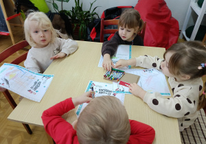 dzieci przy stolikach, rysują prezenty na liście do Mikołaja