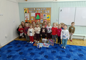 grupa dzieci i pani bibliotekarka pozują do wspólnego zdjęcia w bibliotece