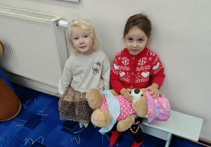 dwie dziewczynki siedzą na ławewczce w bibliotece dla dzieci