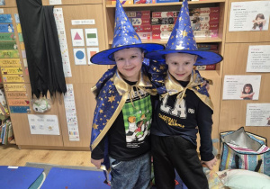 Dwóch chłopców pozuje do zdjęcia, na sobie mają stroje czarowników.